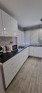 a kitchen with white cabinets and a wooden floor at 2 Camere Splendida casa vacanze in Tenerife del Sur Casa Trilly in Arona