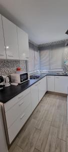 una cucina con armadietti bianchi e pavimenti in legno di 2 Camere Splendida casa vacanze in Tenerife del Sur Casa Trilly ad Arona