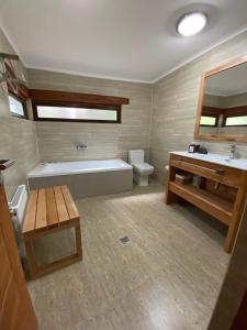 a bathroom with a tub and a toilet and a sink at PURA Hotel in Coihaique