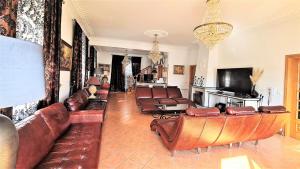 a living room with leather couches and a television at Silver Coast Village in Maceira