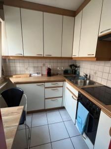 Una cocina con gabinetes blancos, un fregadero y una estufa. en Schweiz (303), en Basilea 6 fotos más