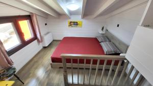 Un pequeño dormitorio con una cama roja en una habitación en Casa de Madera en Kaloskopí