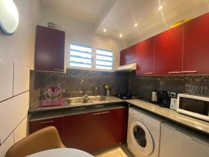 a kitchen with red cabinets and a sink and a dishwasher at Happyhome in Saint-Pierre