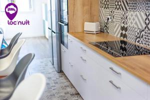 uma cozinha com armários brancos e uma bancada em Loc'Nuit - Chambres Tout Confort - Hyper Centre AGEN em Agen