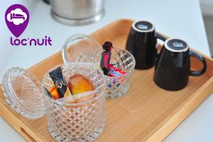 a wooden tray with two cups and a basket of fruit at Loc'Nuit - Chambres Tout Confort - Hyper Centre AGEN in Agen