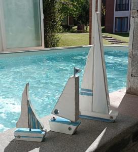 two miniature sailboats sitting next to a swimming pool at Punta Cerezo in Carilo