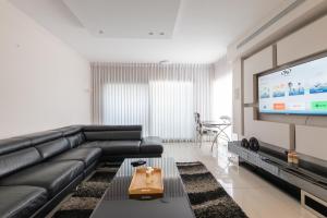 sala de estar con sofá de cuero negro y TV de pantalla plana en O&O Group - Luxury Tower/parking/Shopping Mall/2BR en Qiryat Ono