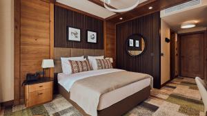 a bedroom with a large bed and a mirror at Grey Hotel Kopaonik in Kopaonik