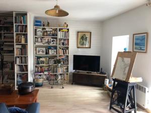 een woonkamer met een flatscreen-tv en boekenplanken bij APPEL A LA BEAUTE in La Vicomté-sur-Rance