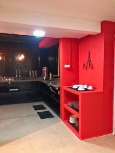 a kitchen with red walls and a red shelf with dishes at Urbanature Filme e Arte BC in Balneário Camboriú