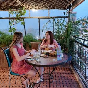 two women sitting at a table on a patio at Auberge chez hammadi in Zagora