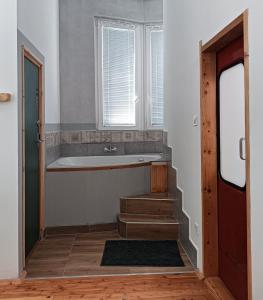 uma casa de banho com uma banheira e escadas com uma janela em ToronySzoba em Szob