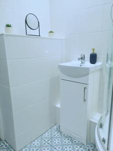 La salle de bains blanche est pourvue d'un lavabo et d'une douche. dans l'établissement Splash of Colour Bournemouth Sleeps 4 Free Parking, à Bournemouth