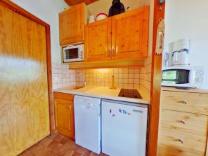 a kitchen with wooden cabinets and a white dishwasher at Appartement Les Saisies, 1 pièce, 4 personnes - FR-1-594-150 in Hauteluce