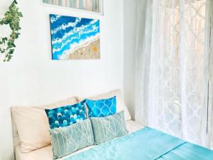 Habitación blanca con sofá y almohadas azules en Balai Lawaan Charming Sanctuary en Iloílo
