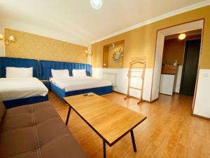a room with two beds and a table and a couch at Hotel Orange Kutaisi in Kutaisi