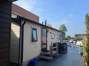 a tiny house with a porch and chairs on a patio at VVP Verhuur Chalet Vinkeveense Plassen in Vinkeveen