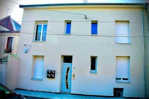 un edificio blanco con ventanas azules y una puerta en Gheddachi en Gentilly