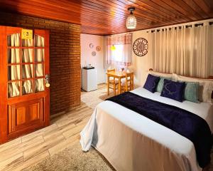 a bedroom with a large bed and a table at Chalés Recanto da cachoeira in Monte Verde