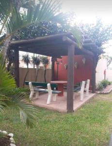 una mesa de picnic y sillas bajo una sombrilla en Apartamento em Capão Novo com piscina, en Capão da Canoa
