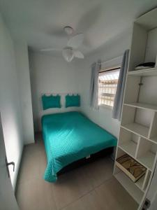 a small room with a green bed and a window at Apartamento em Capão Novo com piscina in Capão da Canoa