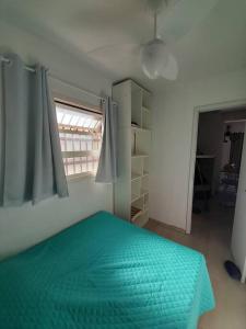 um quarto com uma cama verde e uma janela em Apartamento em Capão Novo com piscina em Capão da Canoa