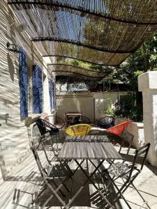 a patio with a table and chairs under a roof at Maison de caractère avec jardin arboré en Avignon in Avignon