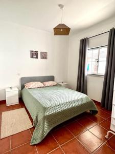 een slaapkamer met een bed met een groen dekbed bij Casa Mourato in Alpedriz