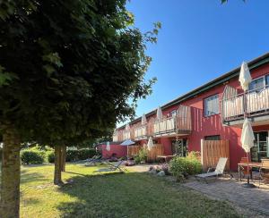 um edifício vermelho com deques e um quintal em Landhaus Storchennest - komfortable Appartements für 2-5 Personen em Reestow