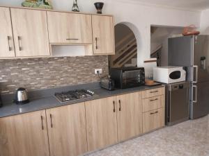 a kitchen with wooden cabinets and a microwave and a refrigerator at Le Tamier - Amazing holidays in Flic-en-Flac