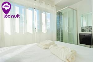 a white bed with a towel on top of it at Loc'Nuit - Chambres Tout Confort - Hyper Centre AGEN in Agen