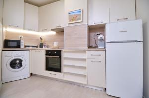 cocina blanca con nevera y lavavajillas en Cozy 1-bed Apartment 2 en Plovdiv