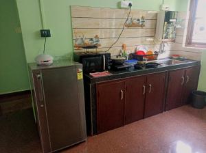 a kitchen with a sink and a stove and a microwave at Benirosa Home Stay Apartment 4 in Cansaulim