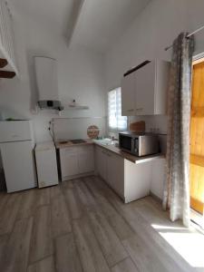 cocina con armarios blancos y suelo de madera en Studio en Petite Camargue en Le Cailar
