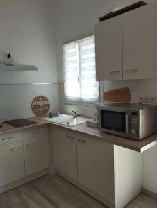 a kitchen with white cabinets and a microwave on a counter at Studio en Petite Camargue in Le Cailar