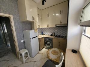a small kitchen with a refrigerator and a dishwasher at Модерн уют в 2х комнатах in Xirdalan