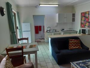 eine Küche und ein Wohnzimmer mit einem Sofa und einem Tisch in der Unterkunft Rosies in George