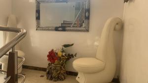 a bathroom with a toilet and a mirror and a vase of flowers at villa palace in Douar Oulad Jaber