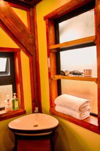 a bathroom with a sink and a toilet and two windows at Shamba lodge in Arusha