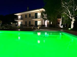 a green swimming pool with a house in the background at Villa Le Torrette in Agropoli