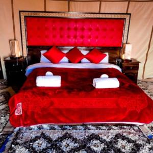 a bedroom with a red bed with red pillows at Authentic Luxury Camp in Merzouga
