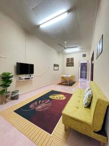 een woonkamer met een bank en een flatscreen-tv bij SRI TEGUH HOMESTAY in Tanah Merah