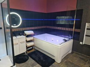 a bathroom with a white tub and a sink at Le nid douillet in Chaumuzy