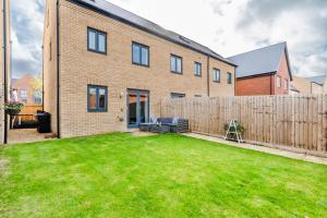 a brick house with a fence and a yard at Spacious 4BR Townhouse Free Parking & WiFi in Milton Keynes