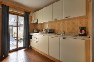 a kitchen with white cabinets and a large window at Bait dal Colocator in Livigno
