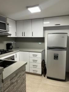 eine Küche mit weißen Schränken und einem Kühlschrank in der Unterkunft Hermoso apartamento ubicado en uno de los mejores sectores de la ciudad in Cali