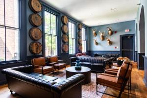 a living room with couches and chairs and large windows at The Woodford Hotel in Versailles