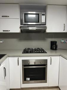 a kitchen with a microwave and a stove at Hermoso apartamento ubicado en uno de los mejores sectores de la ciudad in Cali