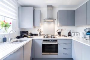 a white kitchen with white cabinets and appliances at Spacious 4BR Townhouse Free Parking & WiFi in Milton Keynes