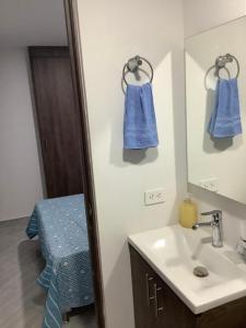 a bathroom with a sink and a mirror with blue towels at Cómoda habitación con baño privado in Sabaneta